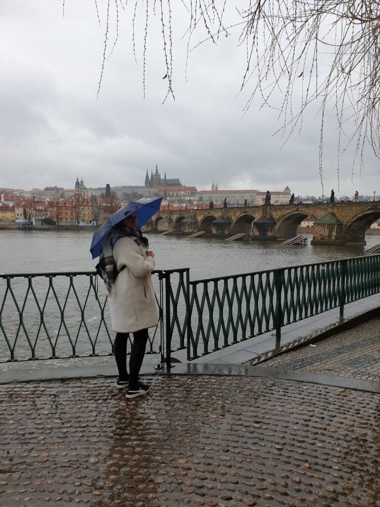 FRUGERE Manon à Prague, sous la pluie, avec, en arrière-plan, le pont Charles et son château