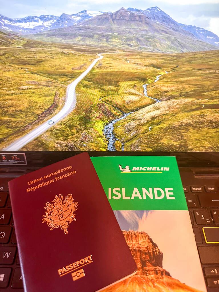Passeport et guide de voyage devant écran d'ordinateur avec paysage montagneux