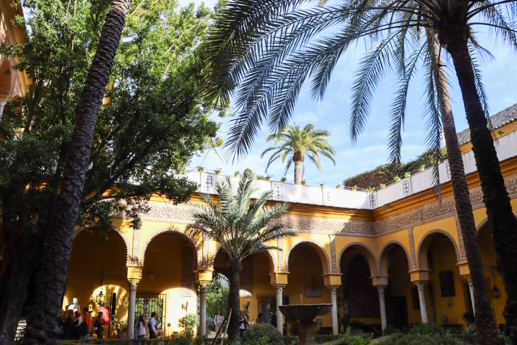 Patio au Palais de Las Dueñas à Séville avec ses palmiers, sa fontaine, et un rayon de soleil