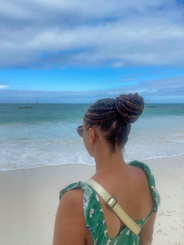 FRUGERE Manon de dos, face à la mer avec des tresses sur la tête