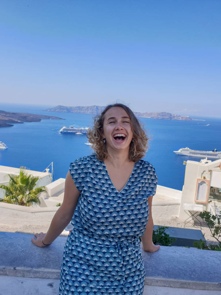 Frugère Manon qui rit à Fira avec la mer Égée derrière