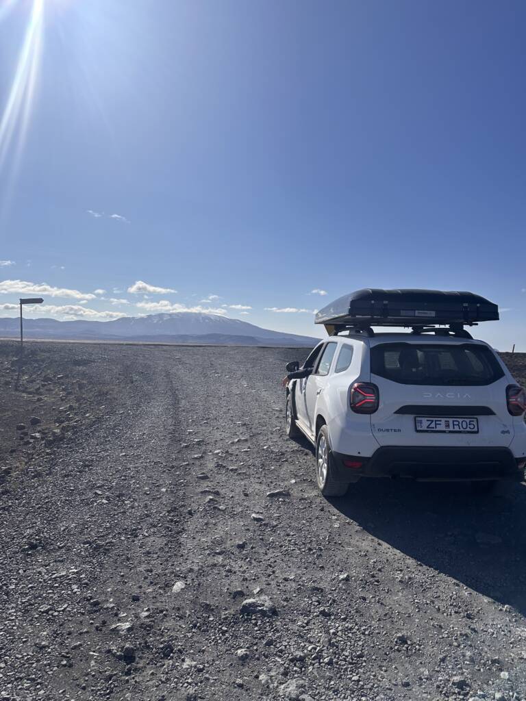 Voiture Dacia Duster en Islande avec une tente sur le toit et le paysage au fond
